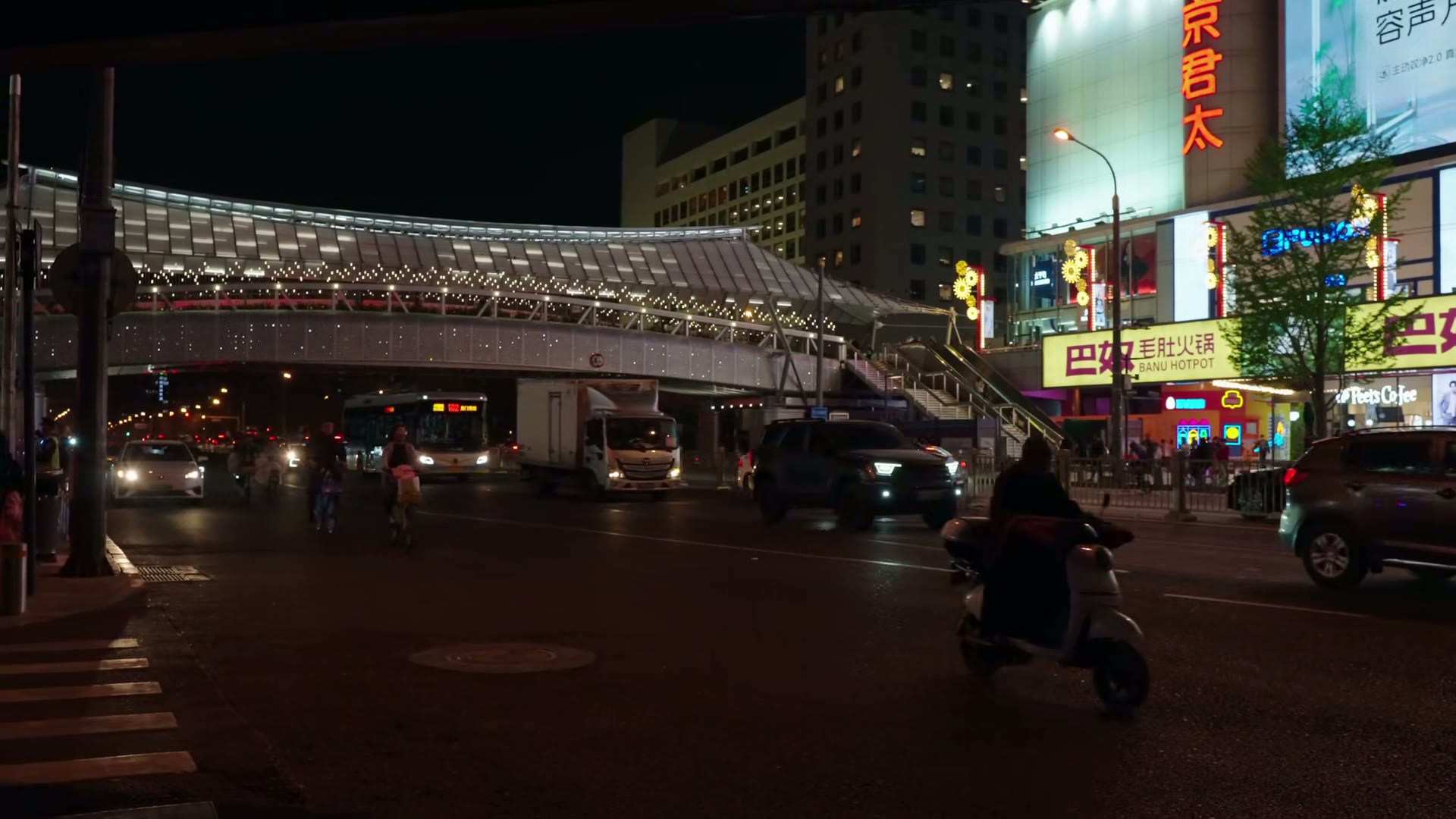 Avenida movimentada na China à noite, com ciclistas, veículos e letreiros urbanos